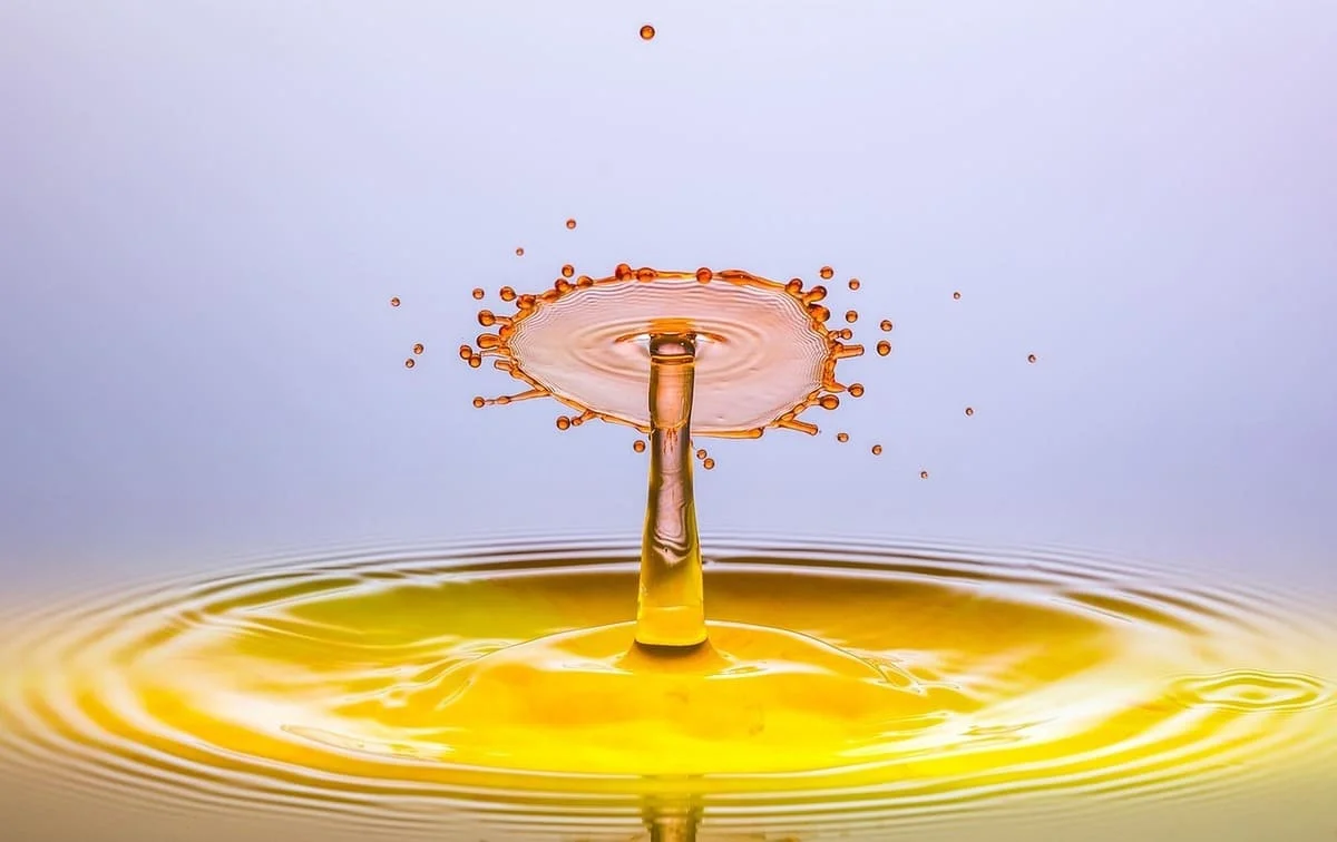 Cómo afecta la hiperestimulación al cerebro representado mediante una gota de agua creando ondas y salpicaduras sobre una superficie líquida