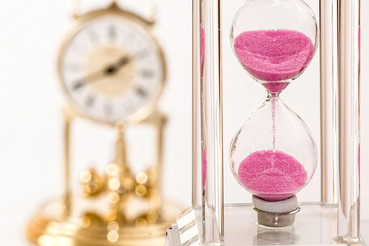 Reloj de arena con arena rosa simbolizando por qué las relaciones duran menos hoy en día y el desgaste emocional en las parejas modernas