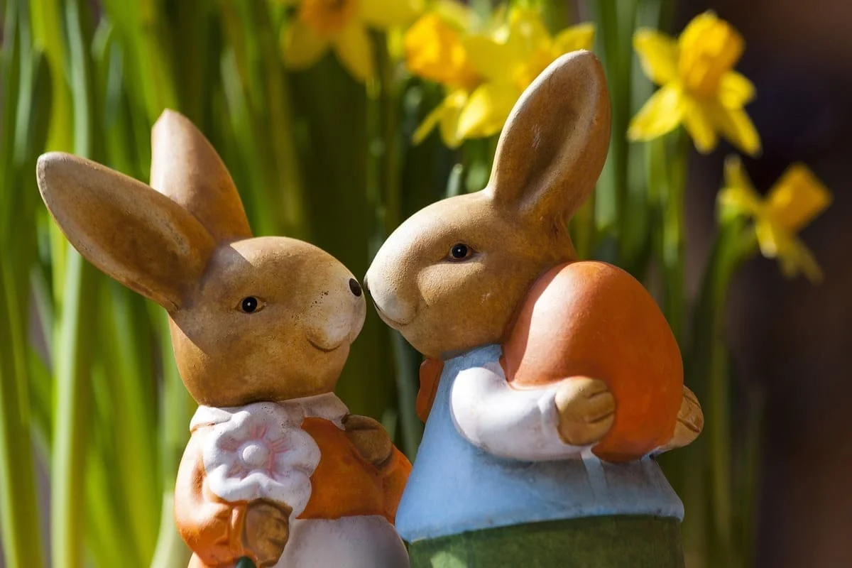 Dos figuras de conejos juntas entre flores amarillas que representan por qué sentimos la necesidad de tener pareja y conexión emocional