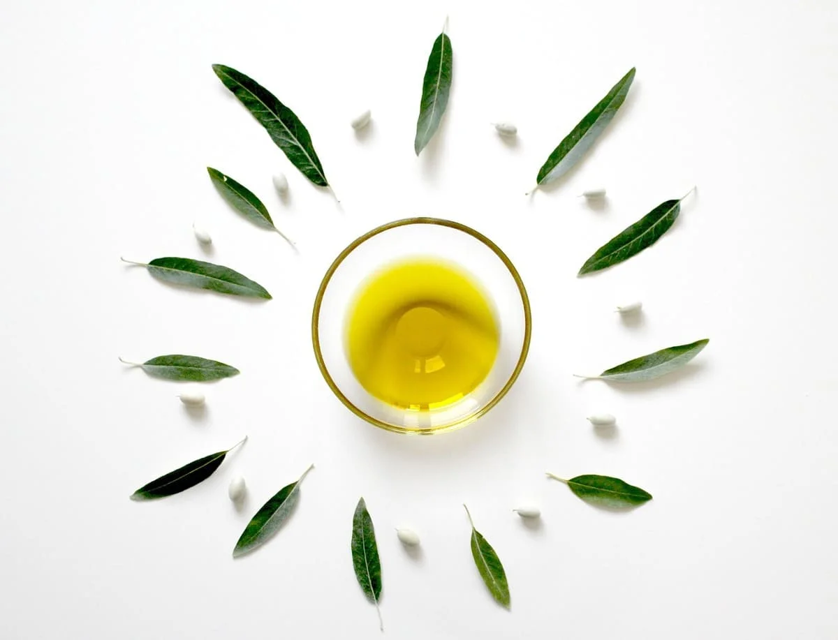 Cómo saber si mis problemas digestivos son por ansiedad: imagen de un cuenco con aceite y hojas de olivo que representa la relación entre la ansiedad y el bienestar digestivo.